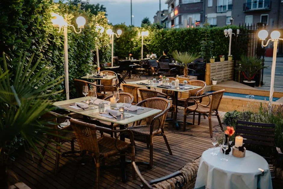 Cozy outdoor restaurant terrace with wicker chairs, tables, and warm lighting for evening dining.